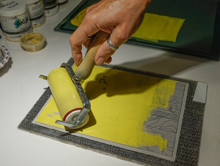 Ink being mixed and rolled onto the linoleum block by hand