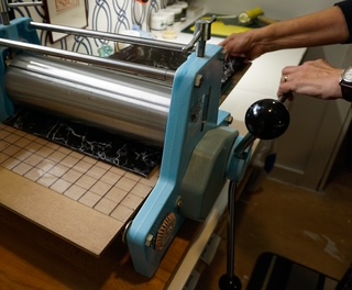 A colour layer being pulled through the press by hand